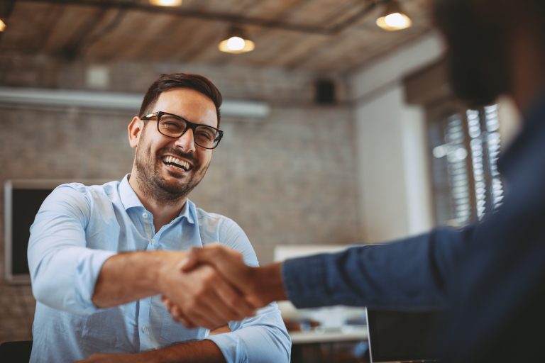 Two business professionals shake hands; represents employee onboarding best practices.